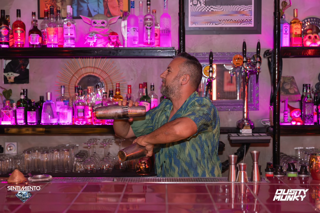 Bartender shaking a cocktail under pink neon lights